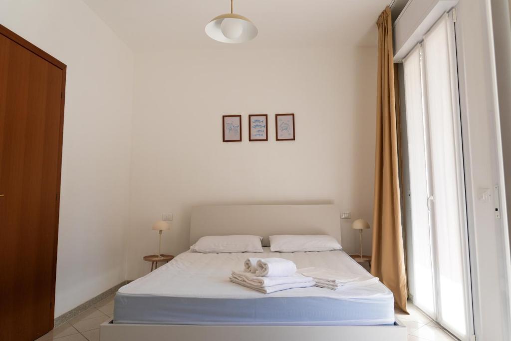 biała sypialnia z łóżkiem i oknem w obiekcie Dainese Apartments, Casa Abigail w mieście Lido di Jesolo