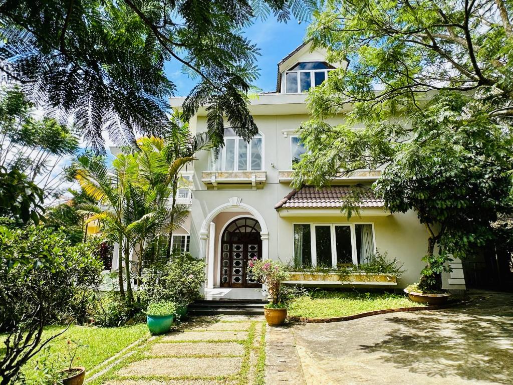 a white house with trees in front of it at Jakaranda Villa Dalat in Da Lat