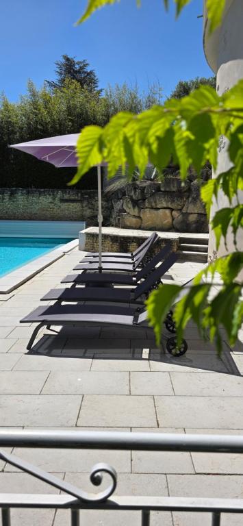 a row of benches with an umbrella next to a pool at Gîte Charmant avec Piscine et Terrasse en Provence MDV in Carpentras