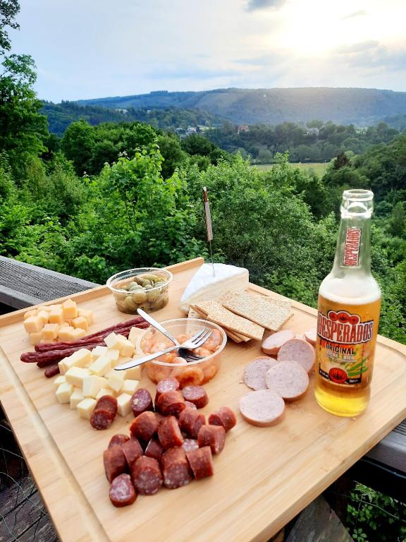 a cutting board with meats and cheese and a bottle of beer at chalet 275 in Rendeux