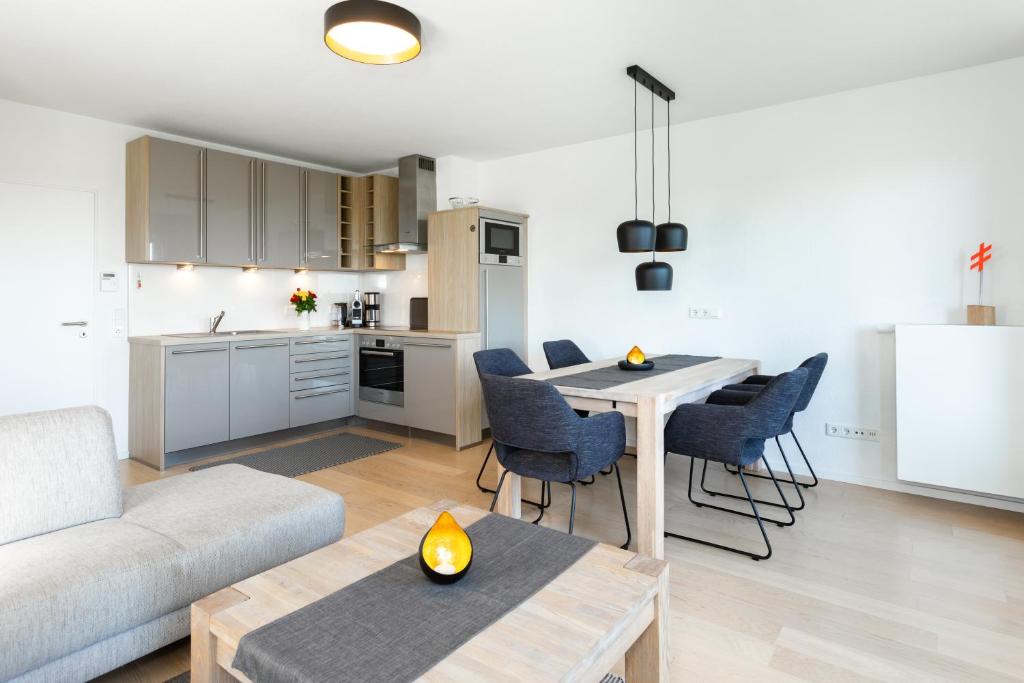 Una sala de estar con mesa y sillas y una cocina. en Deichperle mit bemberg airSPACE Sauna, en Juist
