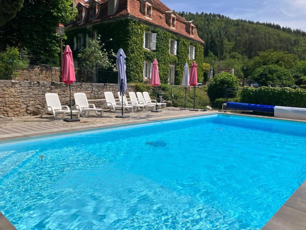 une piscine avec chaises et parasols devant une maison dans l'établissement A L Ombre du Tilleul, à Tour-de-Faure