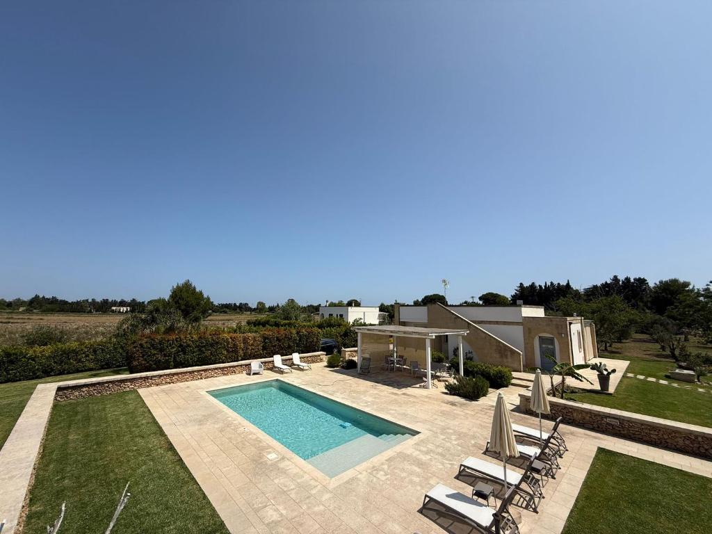 een achtertuin met een zwembad en een huis bij Villa Malepè con piscina in Torre dell'Orso