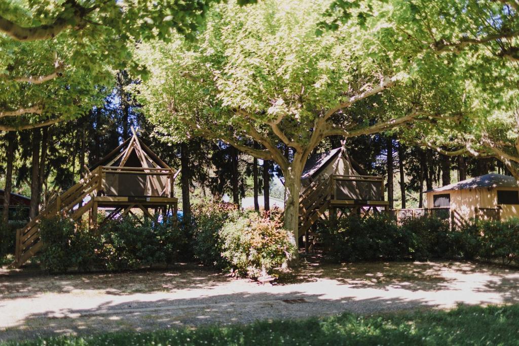 a group of gazebos under trees in a park at Camping Porte des Alpilles by M.A DESTINATION GLAMPING in Saint-Étienne-du-Grès