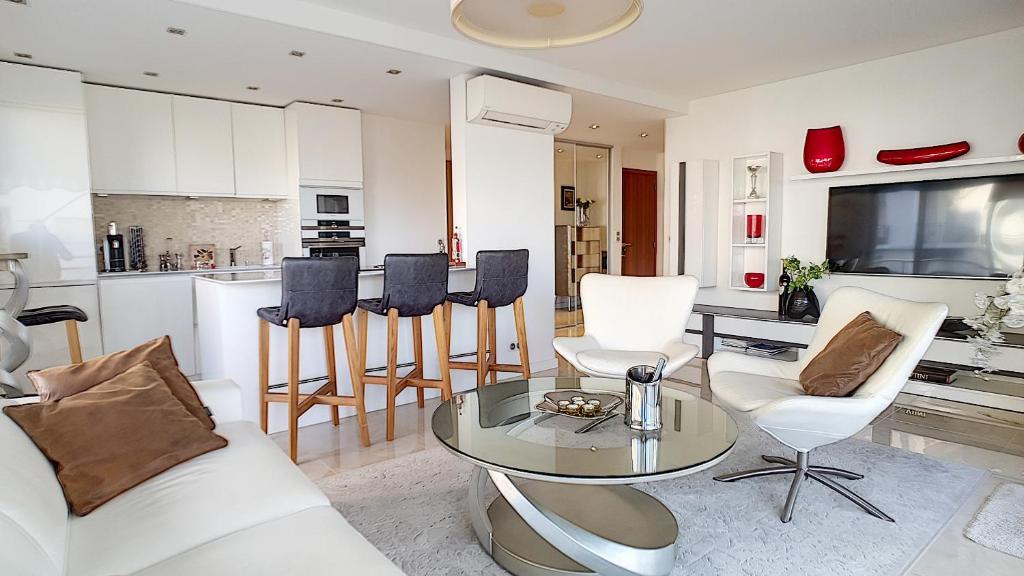 un salon avec une table et des chaises et une cuisine dans l'établissement Bright 2-Bedroom apartment with terrace & parking, à Cannes