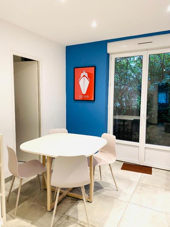 une salle à manger avec une table et des chaises blanches dans l'établissement Appartements à Saint Nazaire, parking gratuit, à Saint-Nazaire