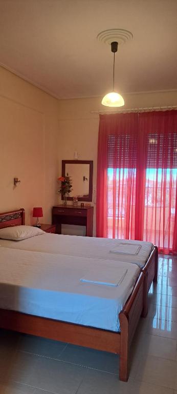 a bedroom with a large bed with red curtains at Golden Sun Apartments in Rovies