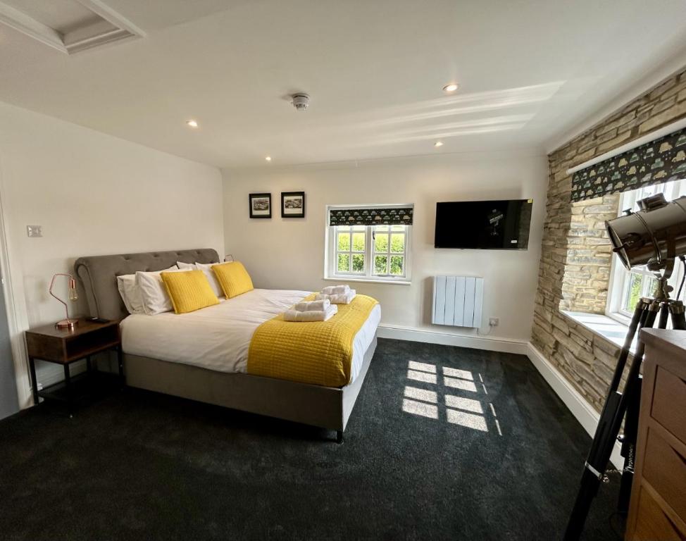 a bedroom with a bed with yellow pillows and a television at The Stag Rooms in Stratford-upon-Avon