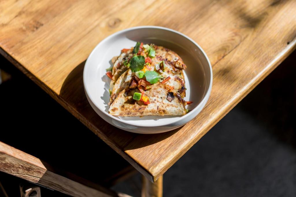a bowl of food sitting on a wooden table at Blossom Eco Luxe Villas by Ekosistem in Canggu
