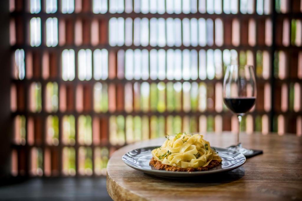 a plate of food and a glass of wine on a table at Blossom Eco Luxe Villas by Ekosistem in Canggu