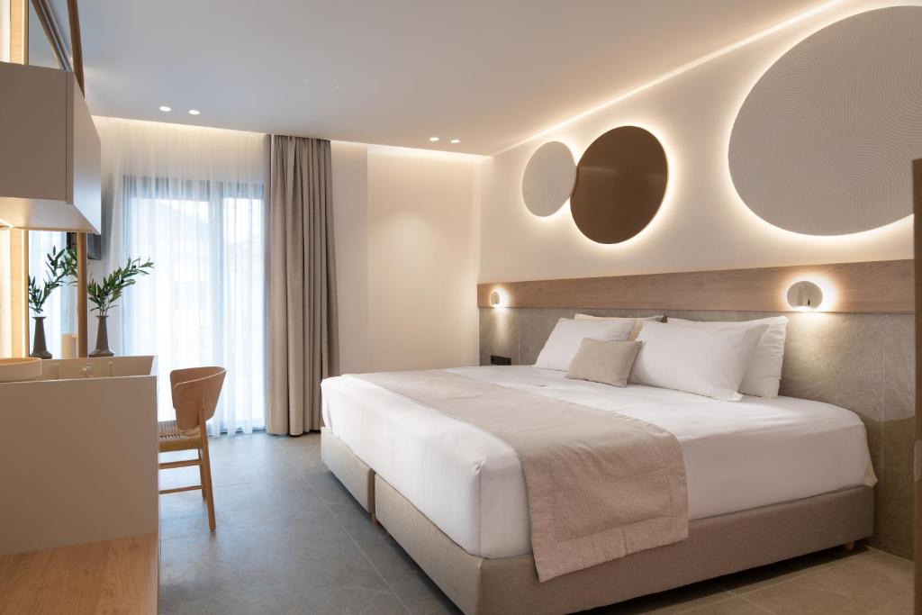 a bedroom with a large white bed and a desk at Olenia Suites in Neos Marmaras