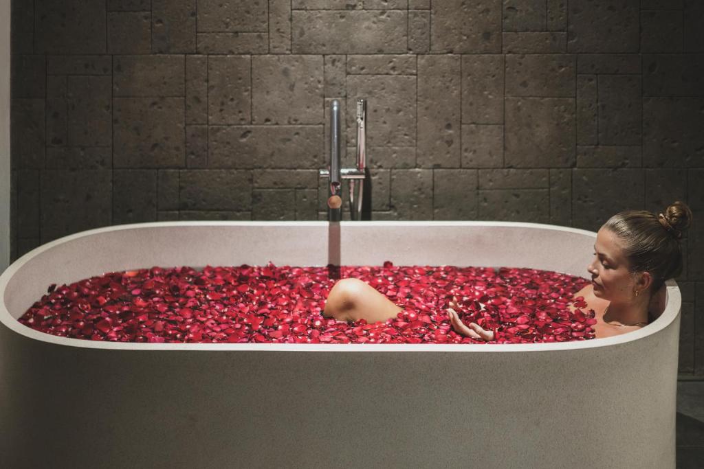 a woman in a bath tub filled with red pills at Blossom Eco Luxe Villas by Ekosistem in Canggu