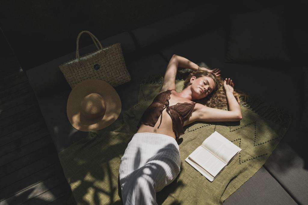 a woman laying on a bed with a book at Blossom Eco Luxe Villas by Ekosistem in Canggu