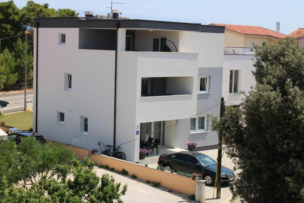 een wit gebouw met een auto ervoor geparkeerd bij Villa SEVEN in Vir