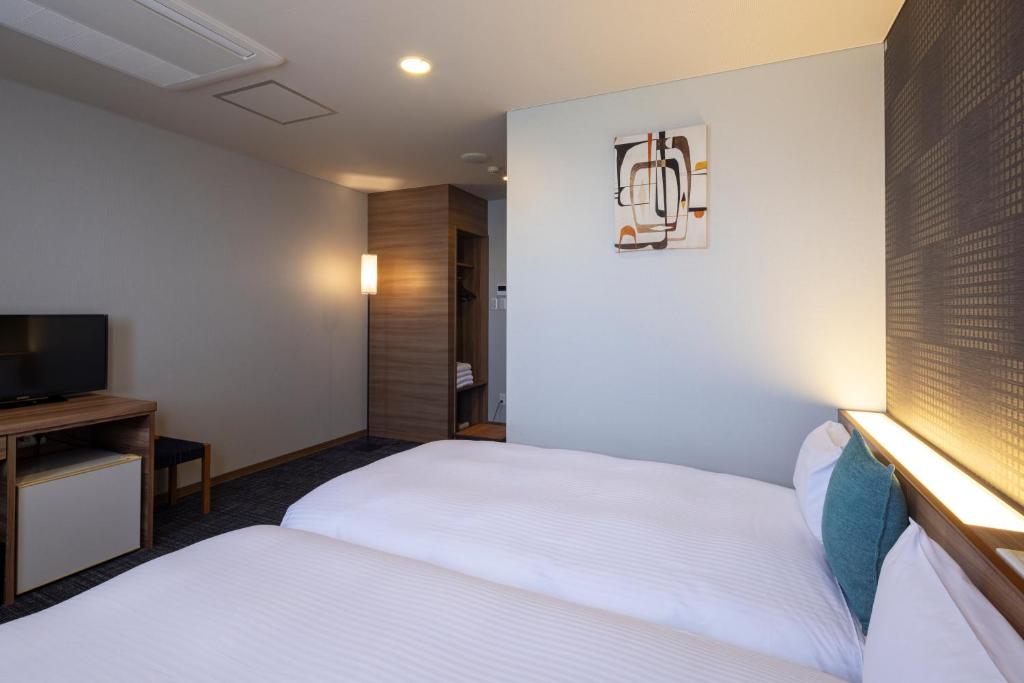 Postel nebo postele na pokoji v ubytování Kiryu Grand Hotel