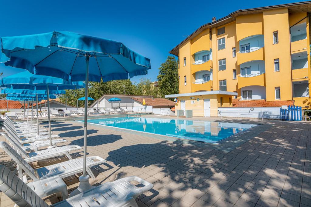 a swimming pool with lounge chairs and a hotel at Hotel & Residence Parador in Cesenatico
