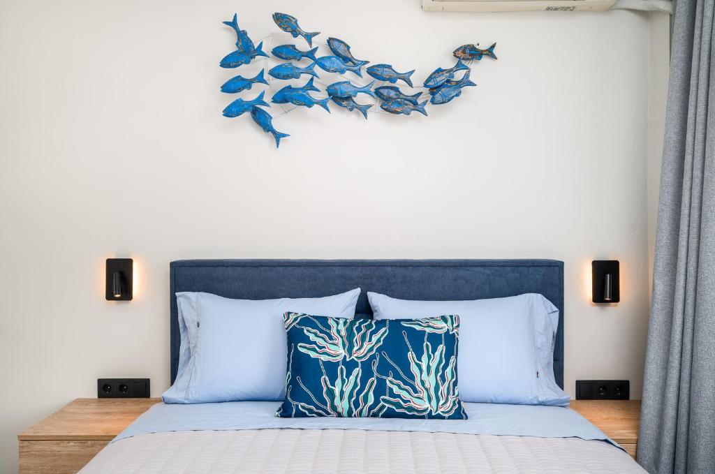 a bed with a blue headboard with fish on the wall at Marietta's Resort by Konnect, Gouvia Corfu in Gouvia