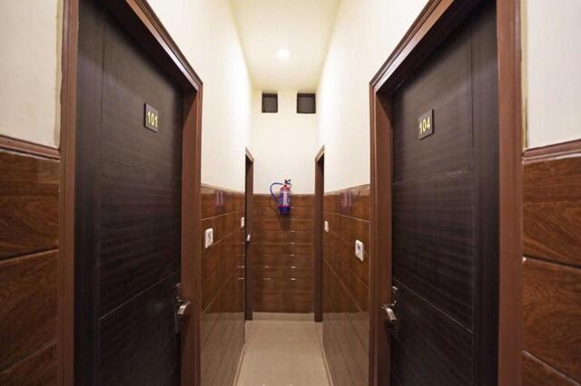 Un pasillo con tres puertas de madera en un baño. en Rainbow Inn, en Nueva Delhi