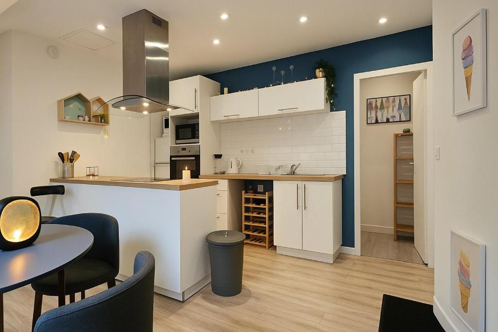 a kitchen with white cabinets and a table and chairs at Nid douillet proche Mer in Saint-Valéry-en-Caux