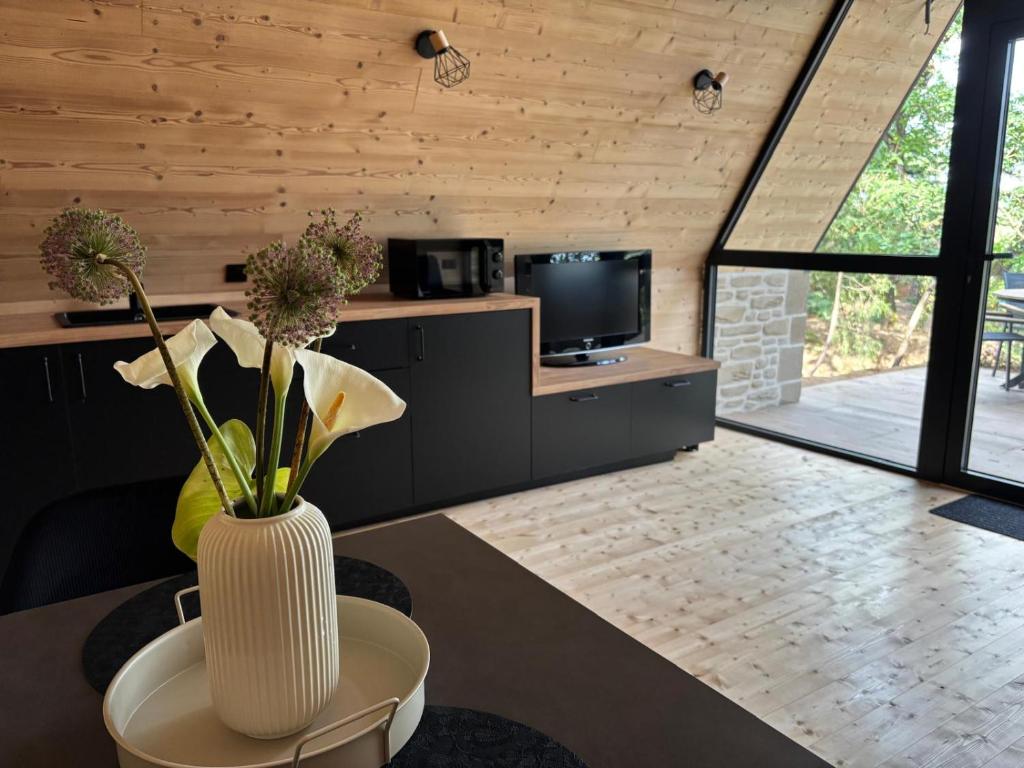 - un salon avec un vase orné de fleurs dans l'établissement Chalet CanopéA 28 m2 au Domaine CollinéA, à Bathernay