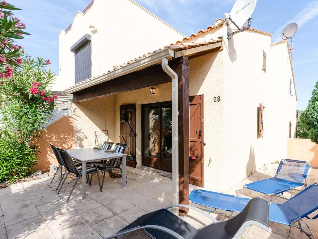 un patio avec une table et des chaises devant une maison dans l'établissement Studio mezzanine avec terrasse, piscine & parking à proximité de la plage - Narbonne - FR-1-409-241, à Narbonne