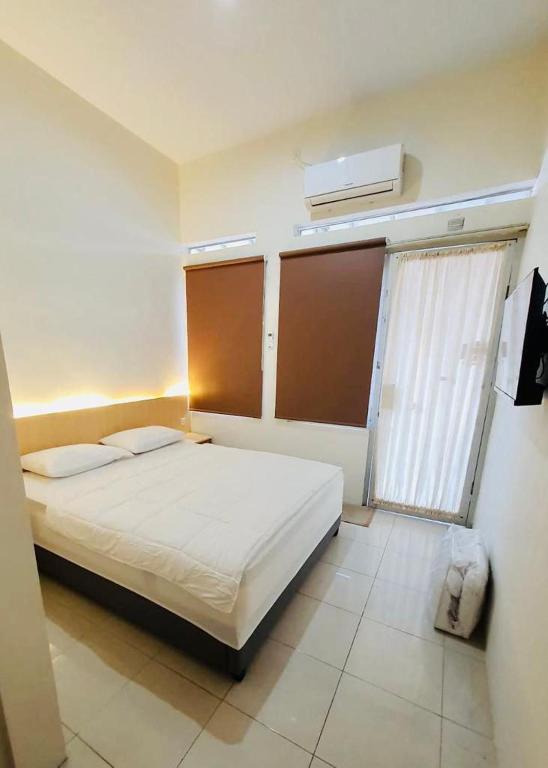 a bedroom with a white bed and a window at Rumah Inap Pesanggrahan in Giri