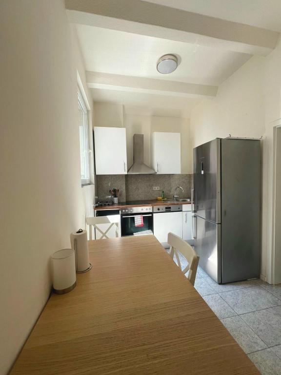 Una cocina con una mesa de madera y un refrigerador. en Rhein Apart 1 near Cologne Messe, en Colonia