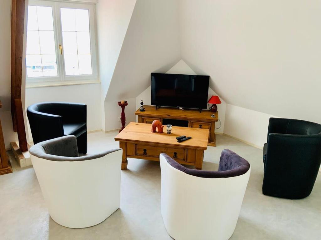 a living room with chairs and a table and a tv at L'écluse appartement vue sur mer in Port-en-Bessin-Huppain