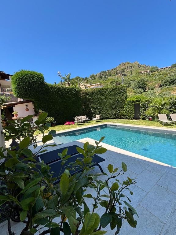 a swimming pool in a yard with bushes at Villa Almond in Taormina