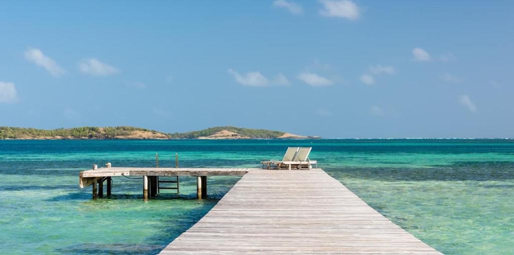 a wooden pier with a bench on the water at Villa Les Agaves front de mer in Le François