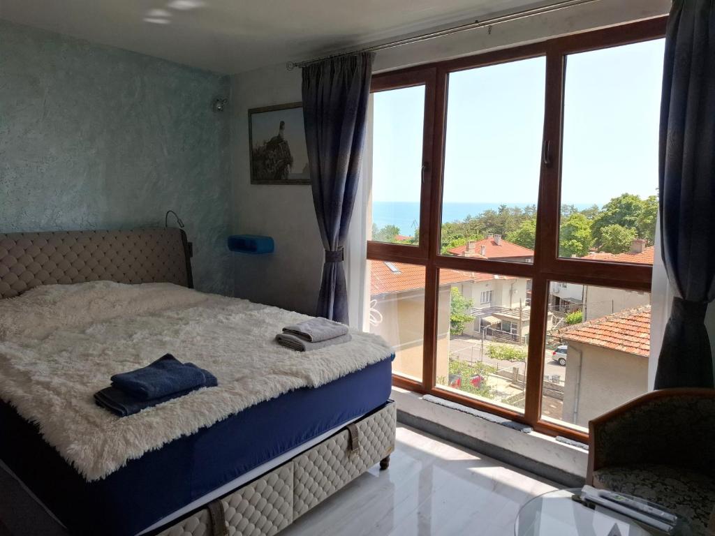 a bedroom with a bed and a large window at Magi Sunrise in Balchik
