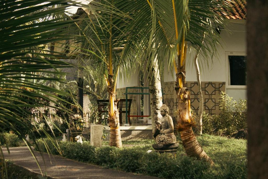 シデメンにあるVilla Joglo tepi sungaiの建物の前の2本のヤシの木の間にある彫像