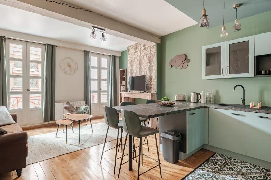 une cuisine avec des murs verts et une table et des chaises dans l'établissement OWL PRESTIGE Dijon, à Dijon