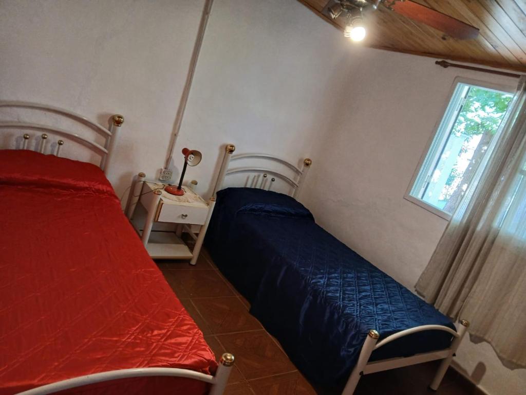 a bedroom with two beds and a window at Cabaña el gato blanco in La Porteña