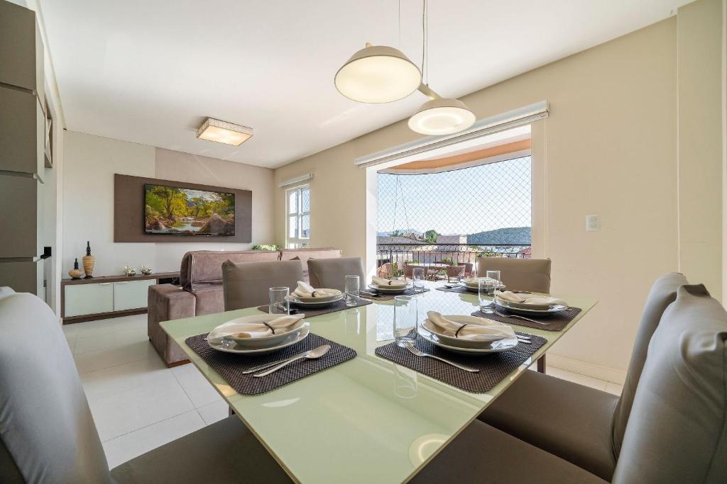 a dining room and living room with a table and chairs at Achei Itapema • Beira-mar e piscina em Porto Belo in Porto Belo