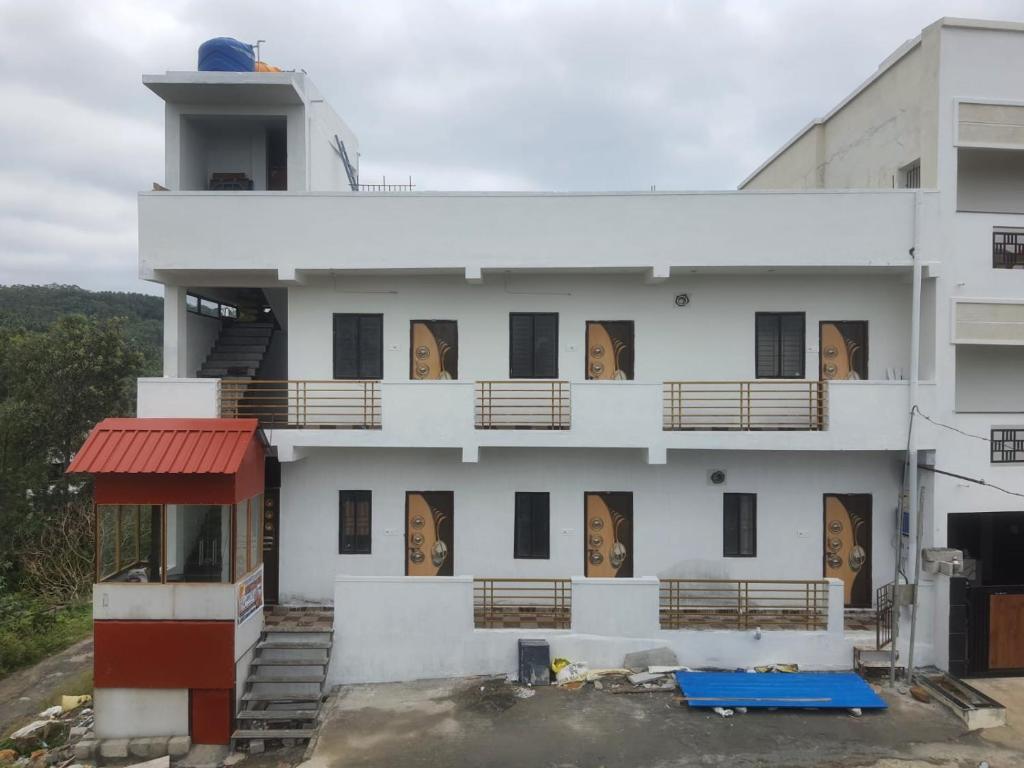 a white building with windows and a red roof at Vista Rooms in Yercaud