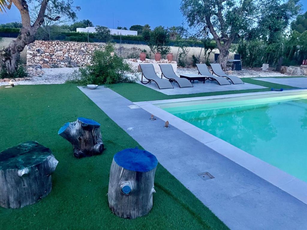 a backyard with a pool with logs and chairs at Tenuta Victoria in Sava