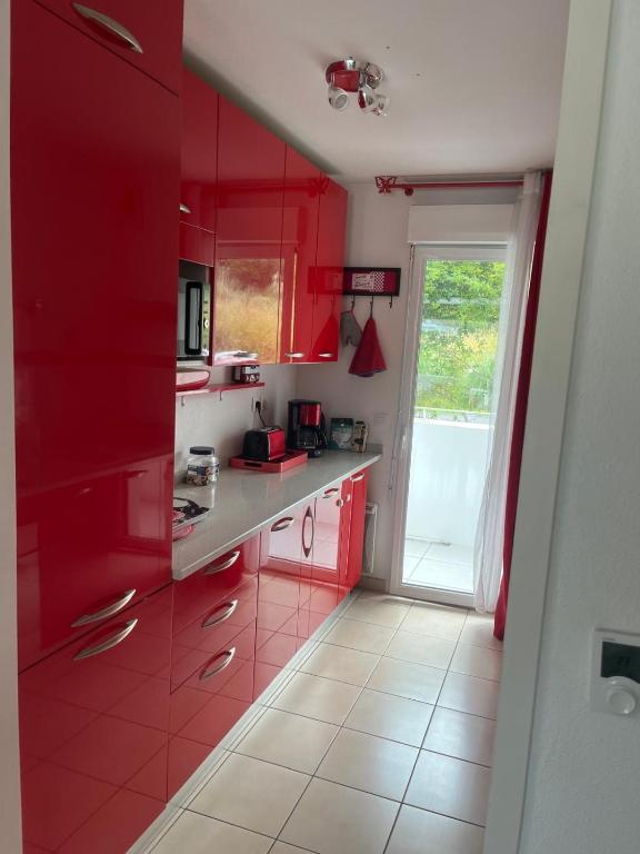 une cuisine rouge avec des placards rouges et une fenêtre dans l'établissement F3 balcons St Jean de Luz, à Saint-Jean-de-Luz