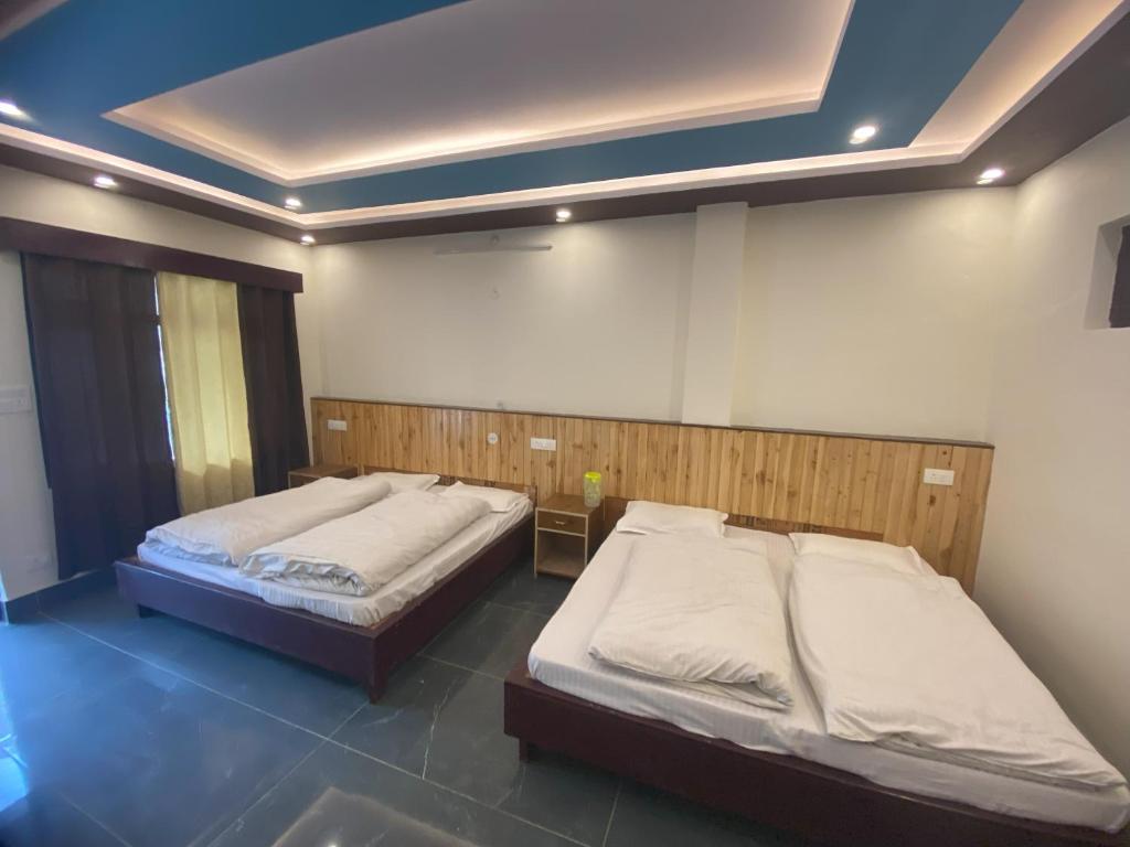 two twin beds in a room with at Hotel Kailash in Harsil
