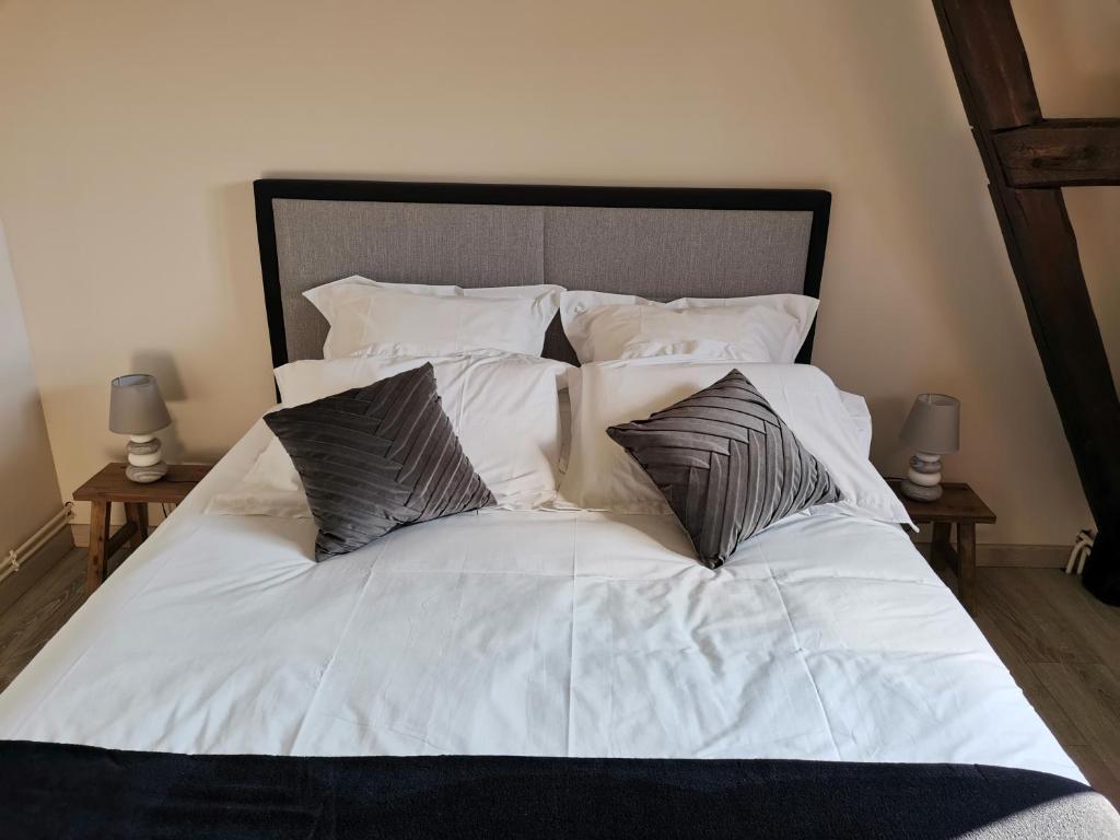 un letto con lenzuola e cuscini bianchi di L'église a Sainte-Marie-au-Bosc