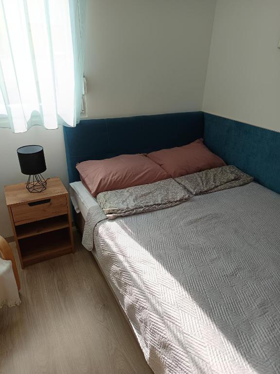 a bedroom with a bed and a night stand and a window at City-Garzon in Kaposvár