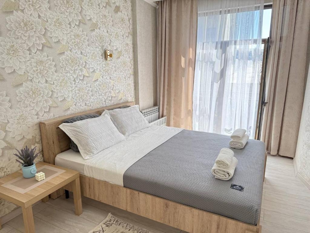 a bedroom with a large bed and a window at Avenue с 1 спальной комнатой in Bishkek