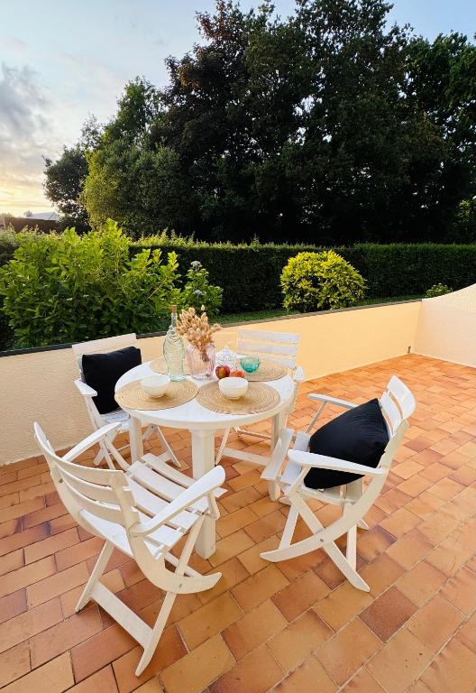 une table blanche et des chaises sur une terrasse dans l'établissement Kerambigorn, à Fouesnant