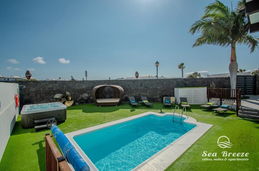 a swimming pool in a yard next to a lawn with a swimming pool at Villa Sea Breeze Jarea in Playa Blanca