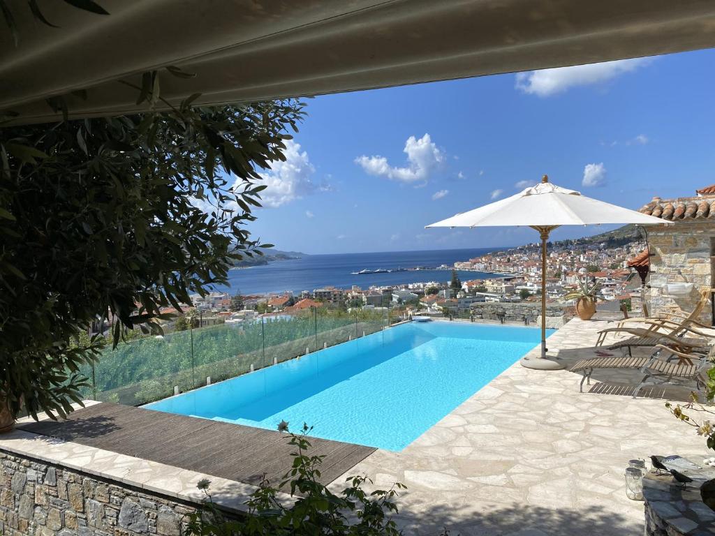 a swimming pool with an umbrella and the ocean at Aegean Panorama Hideaway & Pool in Samos in Vathý