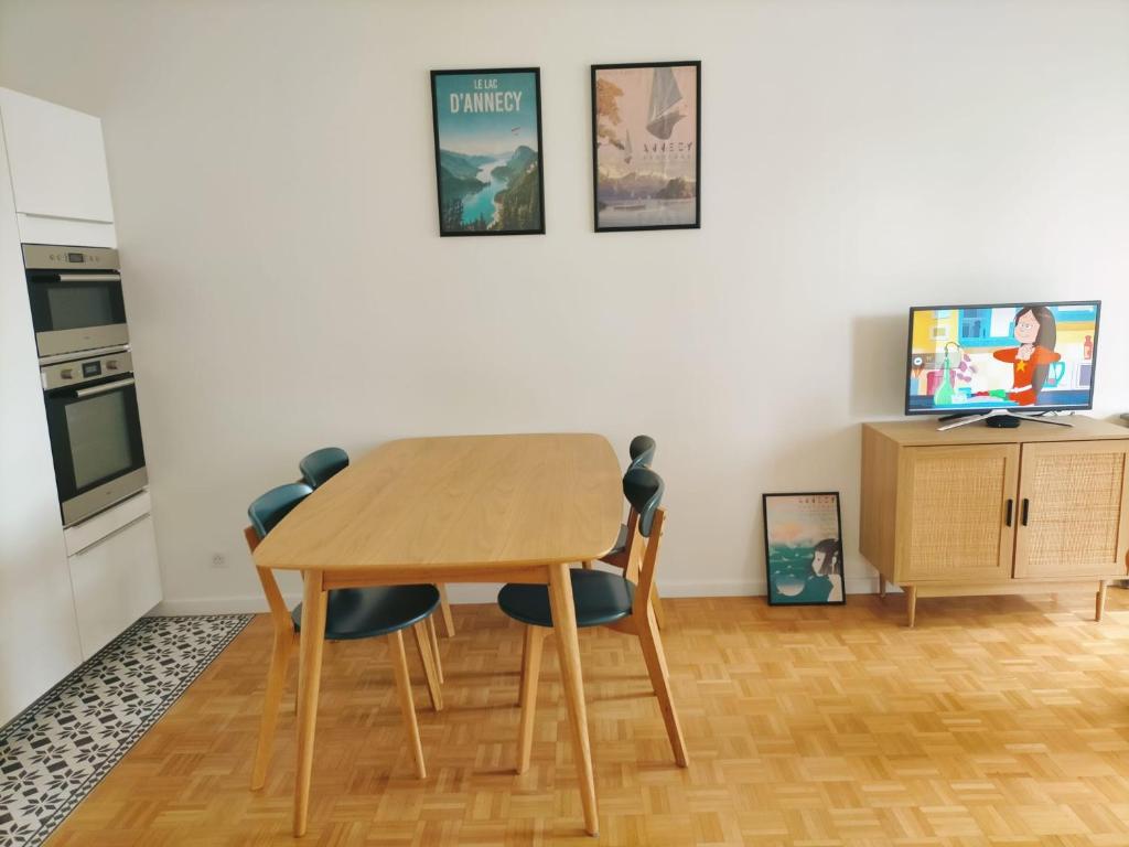 Il comprend une cuisine avec une table et des chaises en bois ainsi qu'une télévision. dans l'établissement T3 Centre ville & Lac, Balcon, Garage, à Annecy