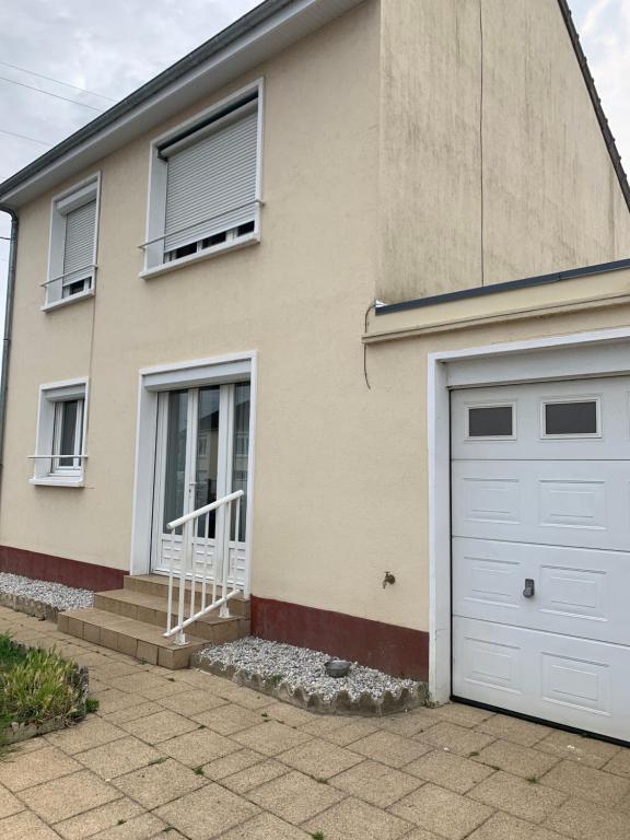 une maison avec une porte de garage blanche dans l'établissement Maison GROSBOIS, à Arnage