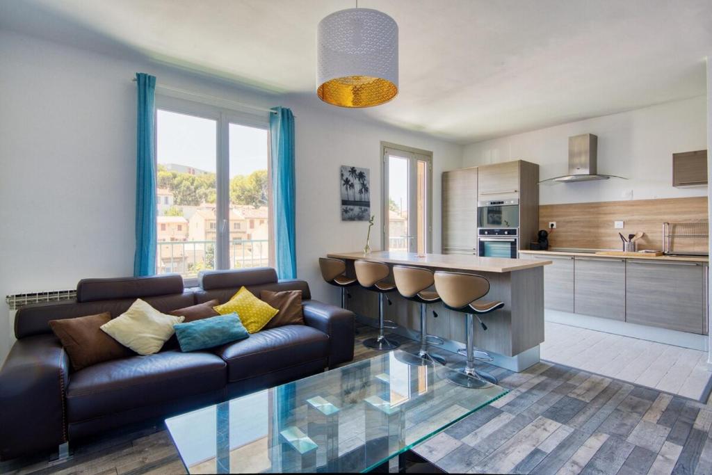 un salon avec un canapé en cuir et une cuisine dans l'établissement Grand T5 de 103 m2 au Bd Guigou avec 4 balcons, à Marseille