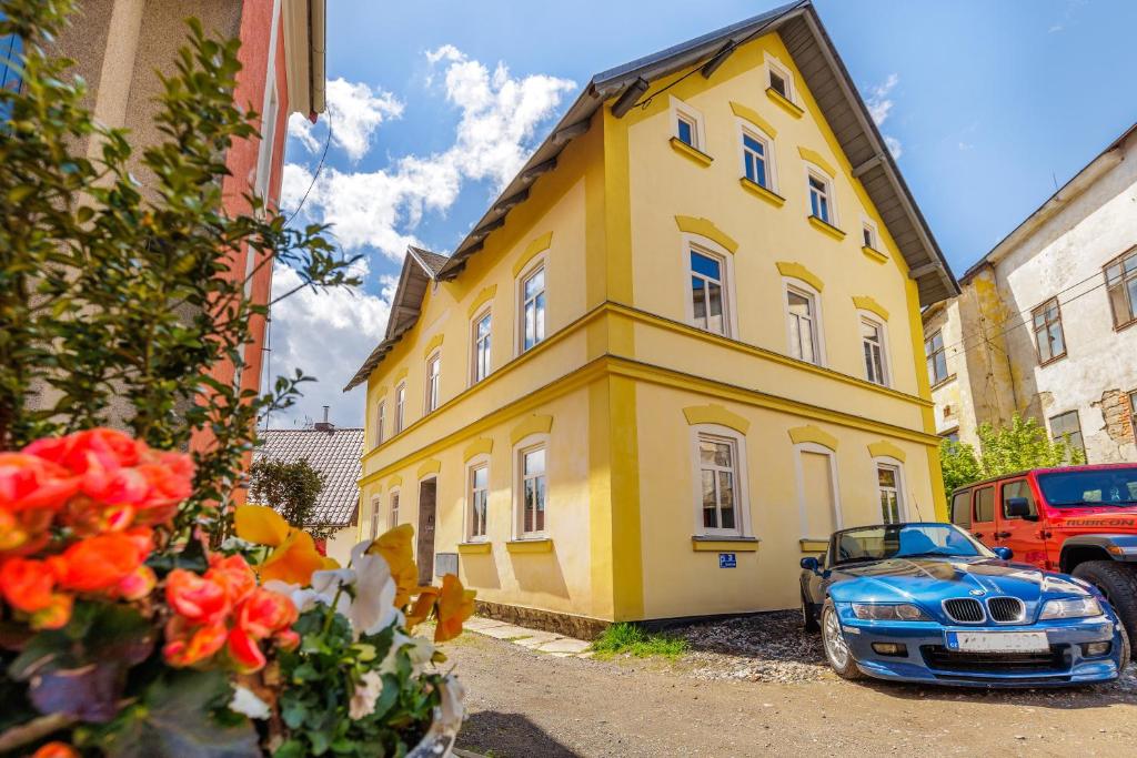 a yellow house with a blue car parked next to it at Sponge Apartmá - Resort Abertham in Abertamy