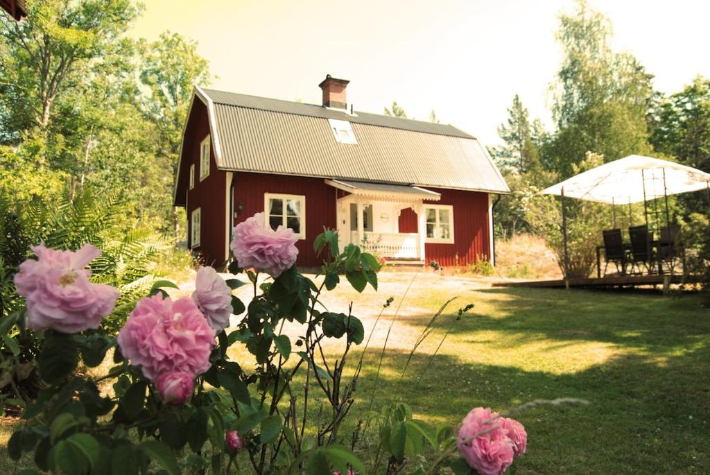 una piccola casa con fiori rosa di fronte di Ferienhaus Grimsebo in idyllischer Alleinlage - Natur pur! a Vimmerby